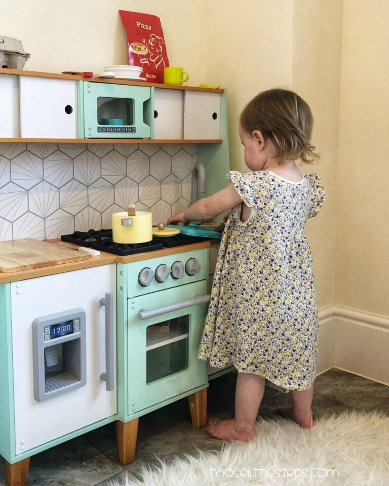 Toddler enjoying independent play in a toy kitchen. Pretend play activity for toddlers.