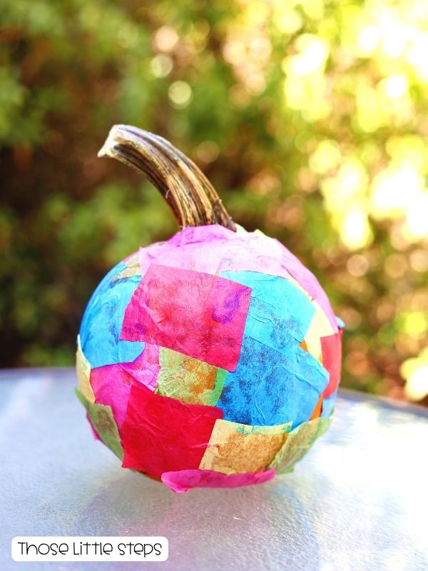 Small pumpkin decorated with colorful pieces of tissue paper for an easy toddler Halloween craft.